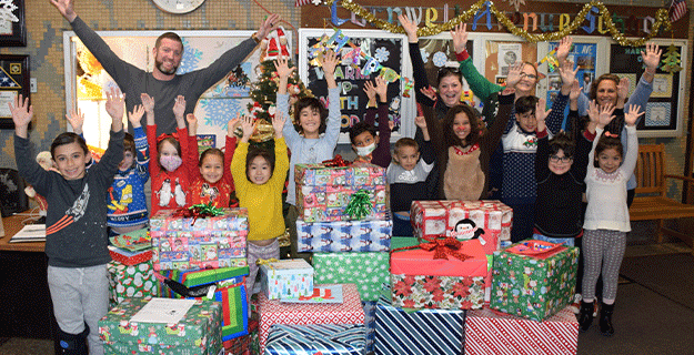 People holding their hands up in celebration as they stand behind presents