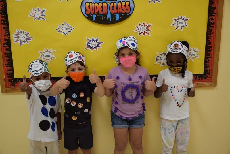 students wearing paper hats and giving thumbs up