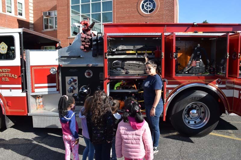 firefighter showing students the fire truck's hoses