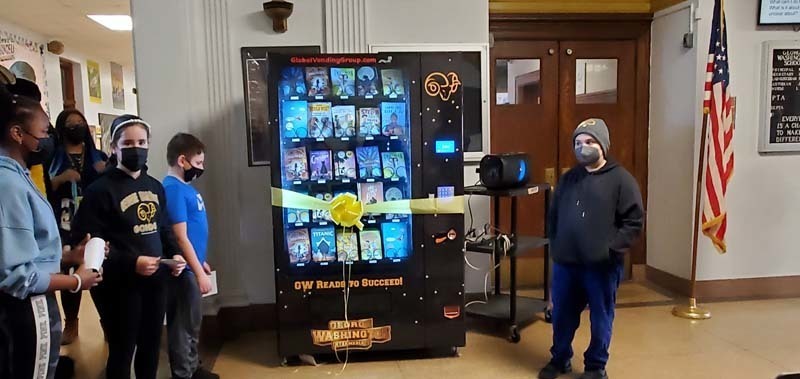students standing near vending machine that dispenses books