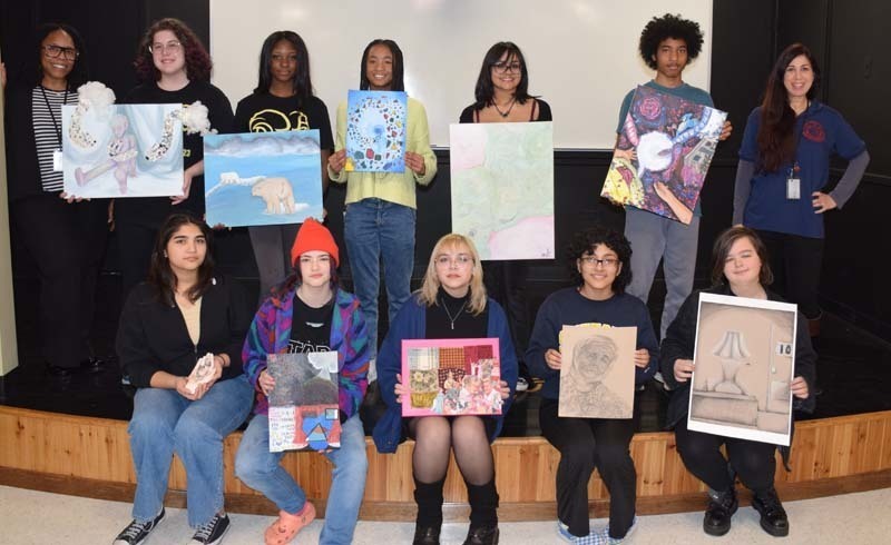 Twelve students Holding Artwork